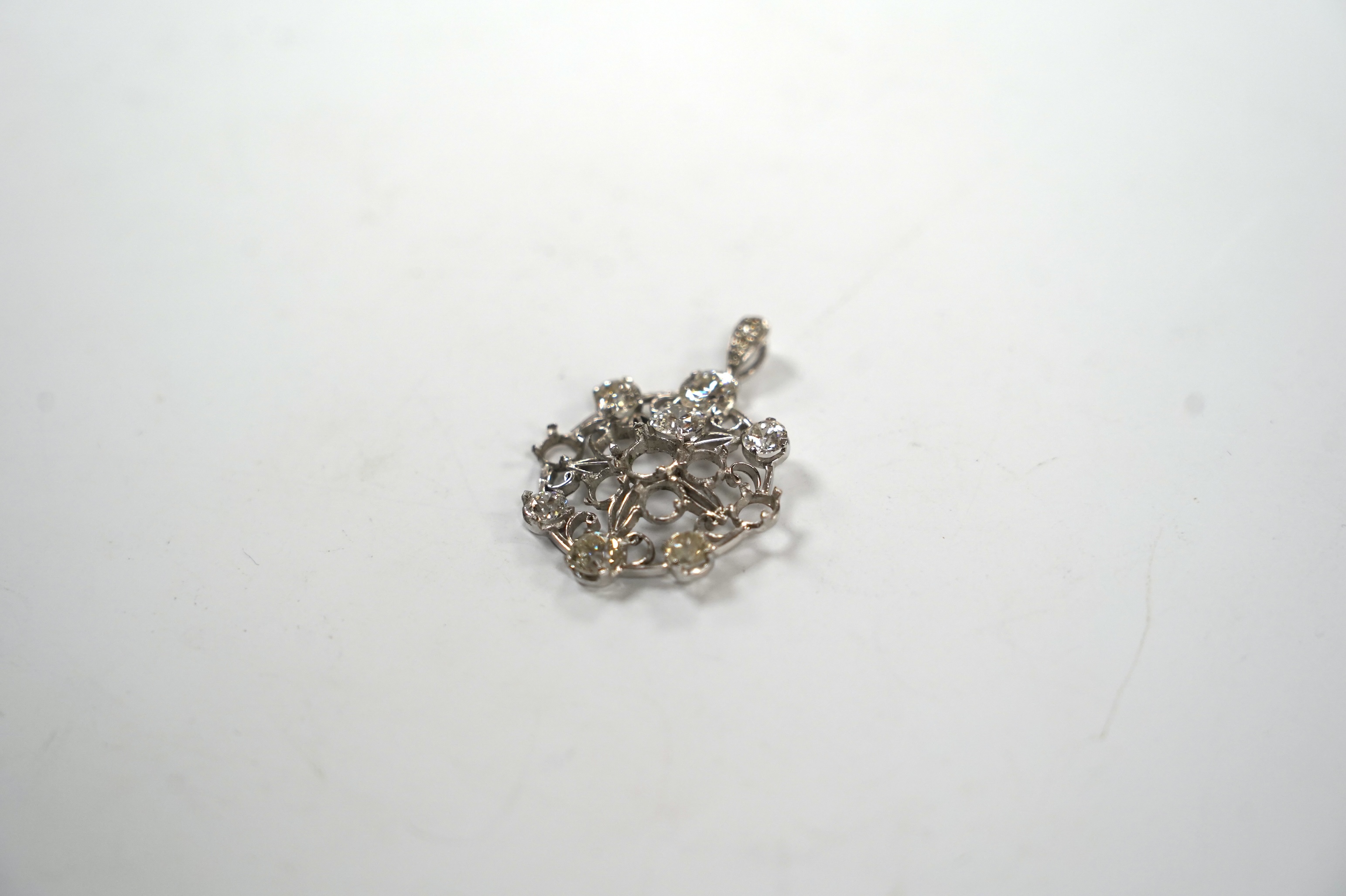 A white metal and diamond cluster set circular pendant (seven stones missing), largest stone diameter approx. 5.6mm, overall 35mm, gross weight 6 grams.